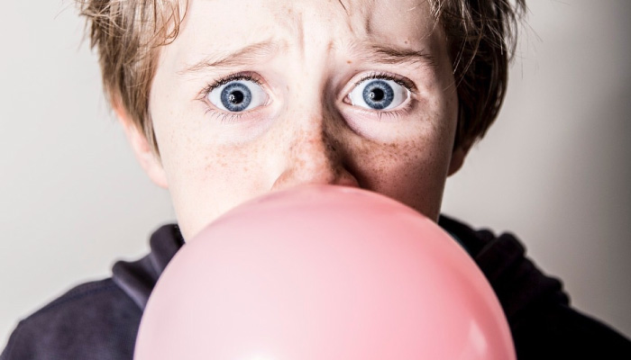 kid blowing a bubble with chewing gum